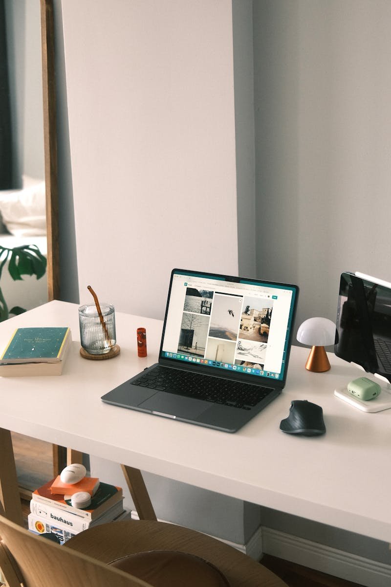 Stylish home office setup with laptop, books, and decor elements on a white desk.